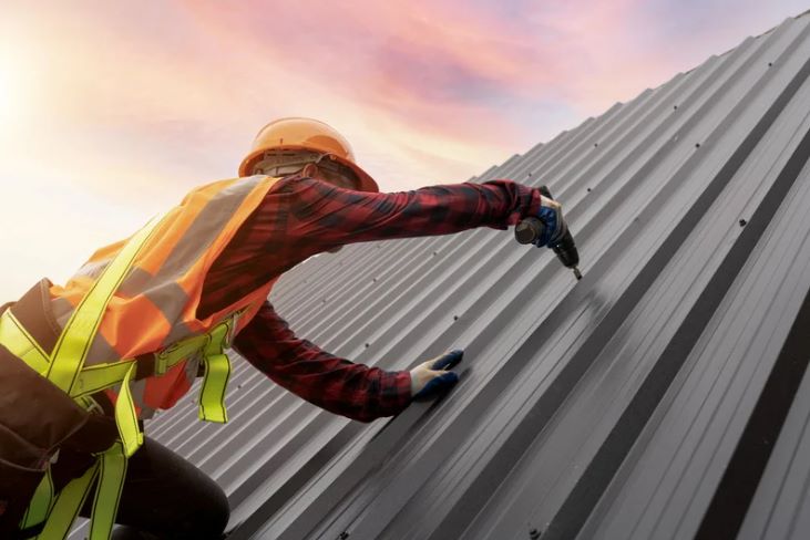 Contractor screwing in the last screw of a metal roof on a commercial building in Hayward, CA