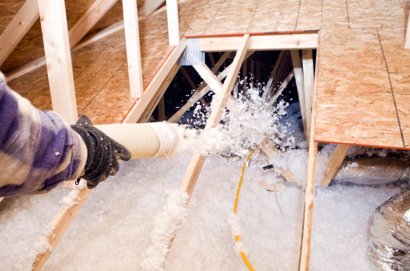 Hayward roofer installing attic insulation to enhance home energy efficiency and comfort.